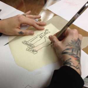 Broadwing Tattoo artist Jaime Mullholand sketches out design.