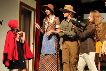 Reporter (Sophia Nelson) interviews Ida (Sky Frishman) and Drake (Isaac Douglass) for "America's Most Feathered."