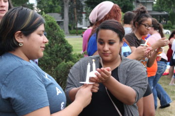 Hannah Cardenas, left, and Beca Rios light candles during vigil.