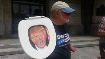 Dick Teeple holds toilet seat with Trump's photo during protest Thursday.