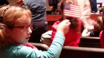 A student waves flag during Veterans Day program.