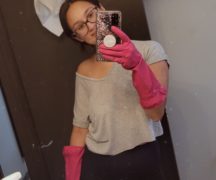 Woman with cleaning supplies takes selfie with camera