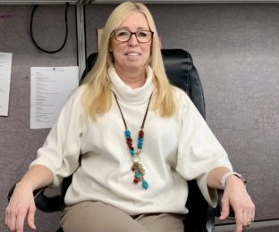 Woman smiles and sits in office chair