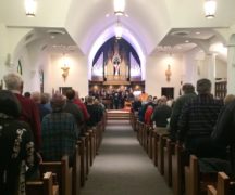 Backs of people in church pews with altar in the background