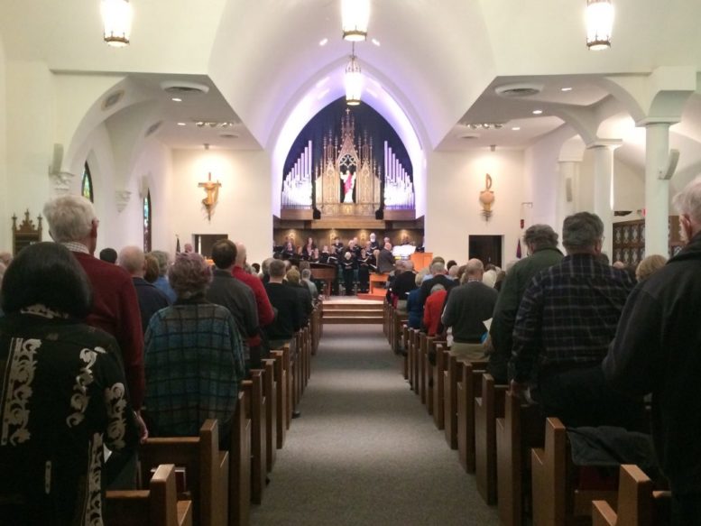 Backs of people in church pews with altar in the background