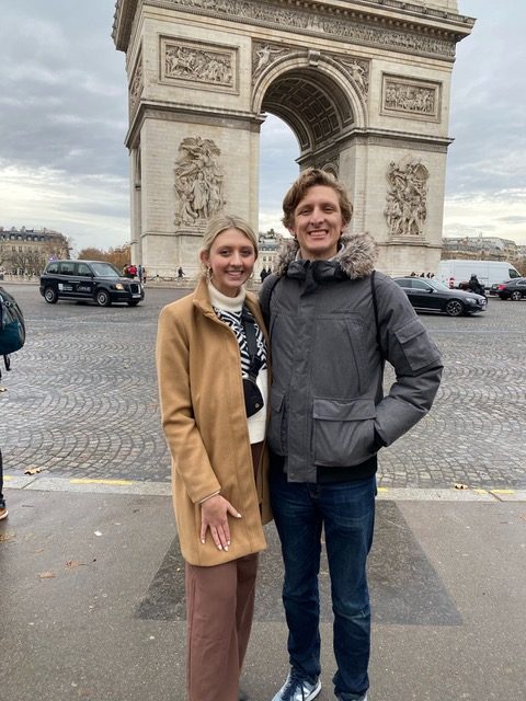 woman and man stand in front of L'Arc de Triomphe