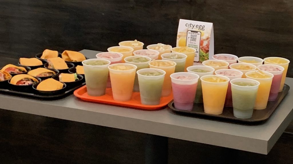 plastic cups full of green, orange, red juices on a tray