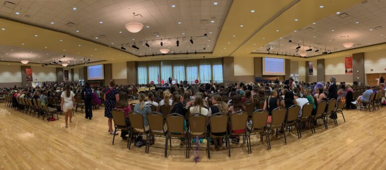 Room full of girls state members seated watching program on stage