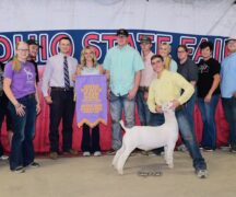 line of people standing behind man holding a goat in the front