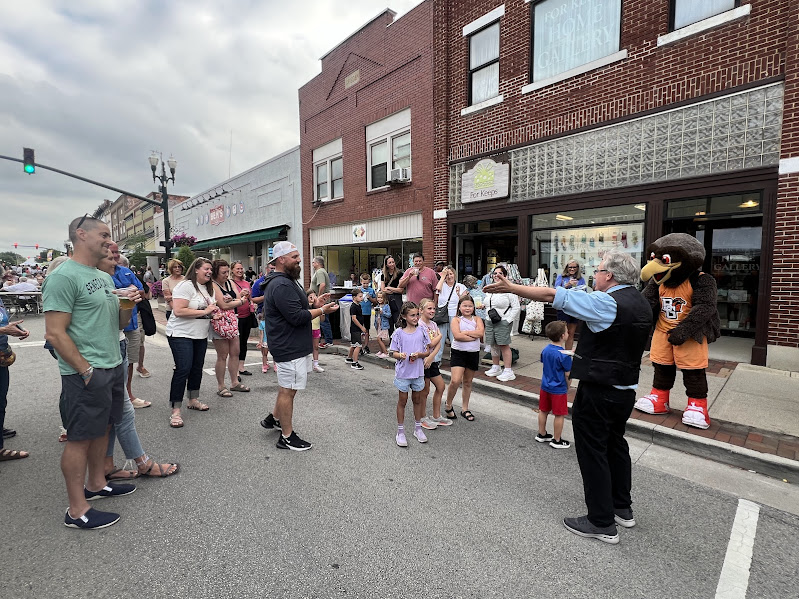 Photo shows crowd gathered around a magician who is performing an illusion