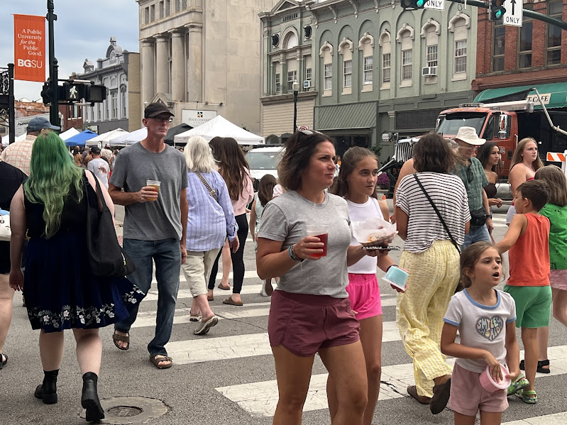 People cross Wooster St. in the crosswalk while holding food and drinks