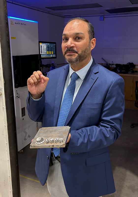 Dean Mokhtar of the College of Engineering and Innovation, with parts made by metal 3D printer.