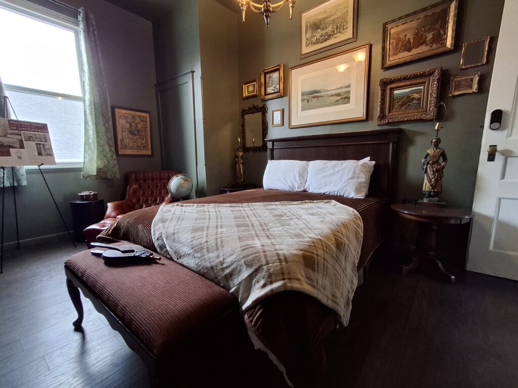 Bedroom with dark floors, lots of art on the wall.