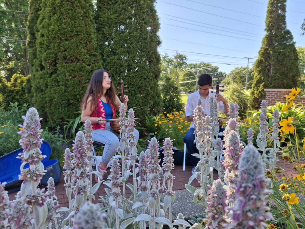 A young woman and young man playing Persian instruments.