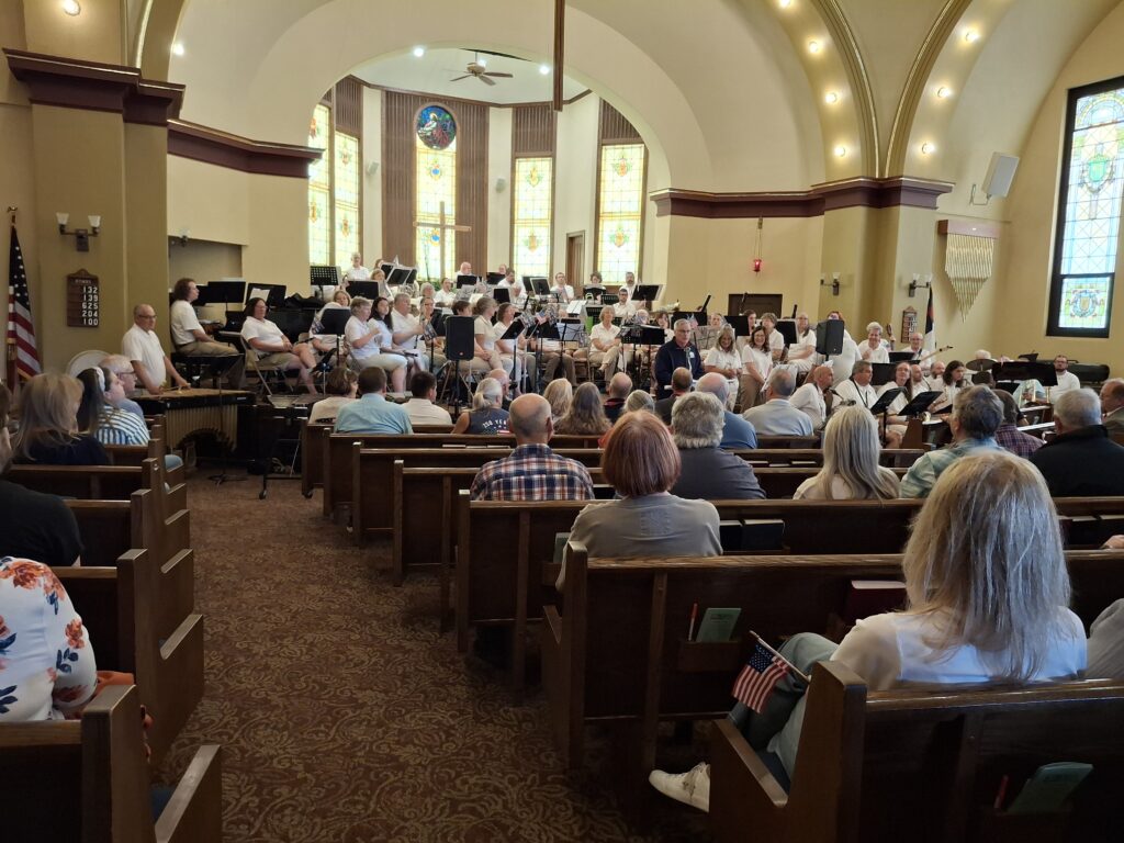 A church full of people waiting to hear a community band.