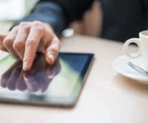 Man with tablet computer reading news at morning in cafe