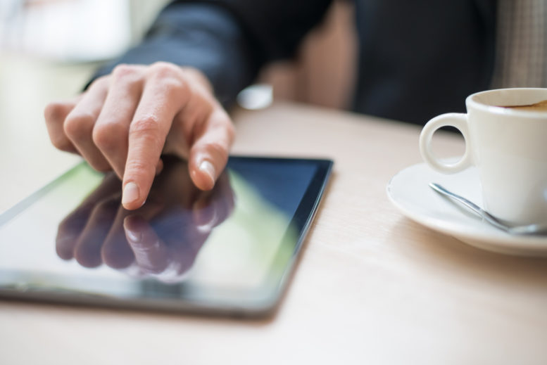 Man with tablet computer reading news at morning in cafe