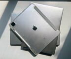 two silver laptops and a silver ipad are stacked on each other, closed