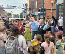 a magician holds two sets of three rings and performs in the middle of a crowd