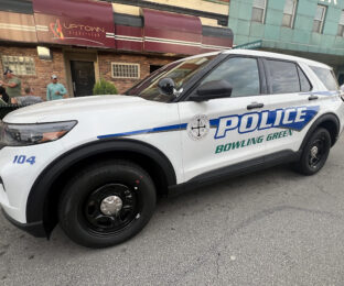 a police car is parked in front of a downtown bar