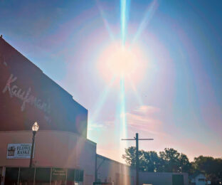photo shows the side of a building with the sun shining brightly above it