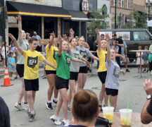 Dancers are synchronized: all have one arm up and one arm extended to the side.