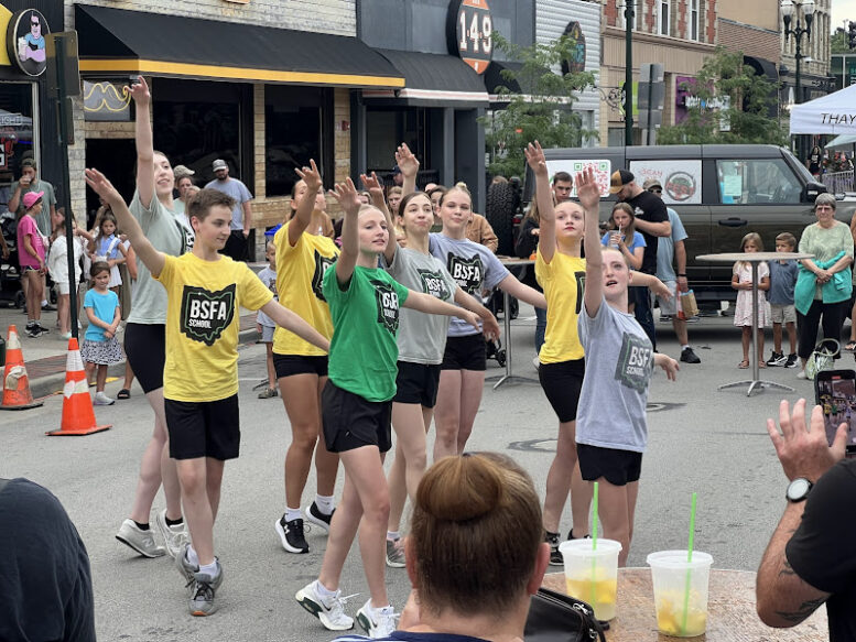 Dancers are synchronized: all have one arm up and one arm extended to the side.