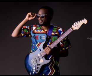 Photo of Sam Shaba holding a guitar.