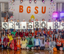 Large group of students dressed in colorful costumes holding up signs with $39680.87.