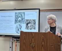 Dr. Rebecca Mancuso in front of a slide describing hazing throughout history